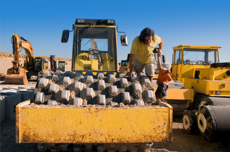 Father lifts his boy on dirt roller on a motorway construction site