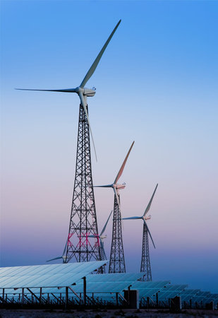 Modern windmills and solar panels on sunset