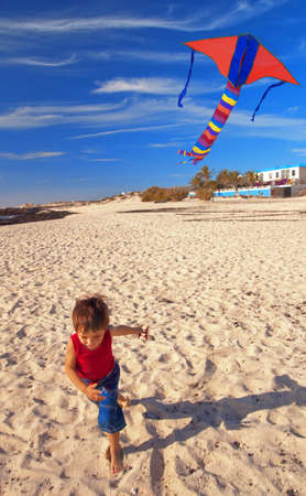 Little boy on a beach runs with a kiteの写真素材