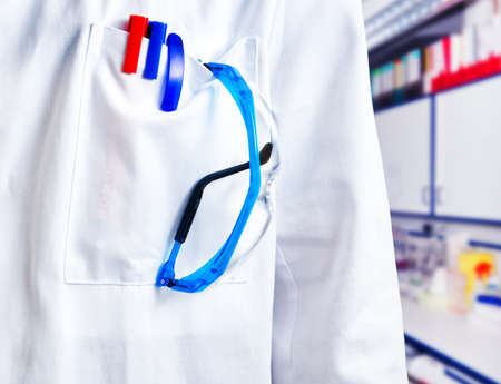 Markers, pens and spectacles in the pocket of a scientist in white coatの写真素材