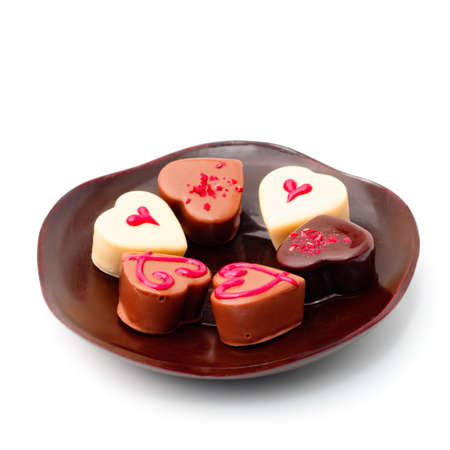 Brown plate with assorted heart-shaped chocolates on white backgroundの写真素材