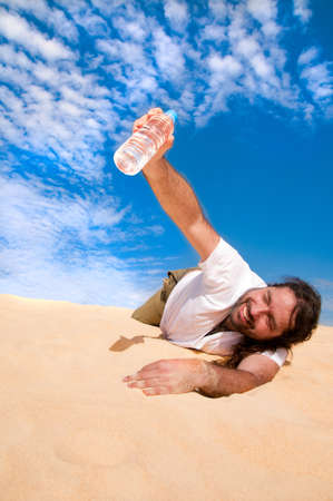 Thirsty man in the desert with a bottle of waterの写真素材