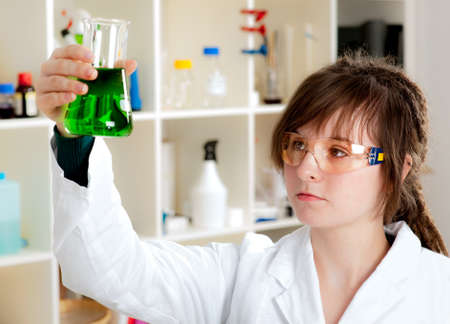Young scientist mixes green liquid in a conical flaskの写真素材