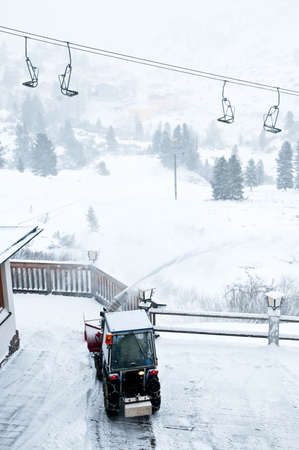 Tractor cleans snow from wooden platform by the ski lift in resort Oberthauern in Austrian Alpsの写真素材