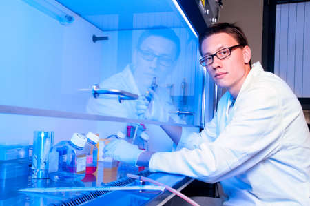 Young tech works with cell cultures under sterile hoodの写真素材