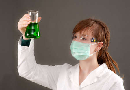 Young tech mixes green solution in a conical flaskの写真素材