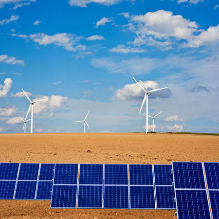 Solar panels on Autumn field with windmills on the horizonの写真素材