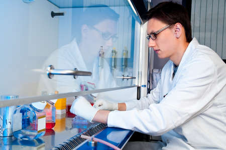 Young tech works with cell cultures under sterile hoodの写真素材