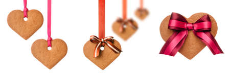 Baked gingerbread hearts decorated  with bows and ribbons on white backgroundの写真素材