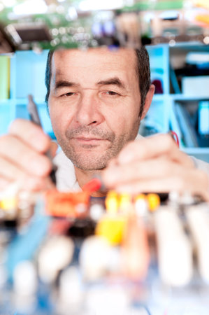 Senior male tech tests electronic equipment