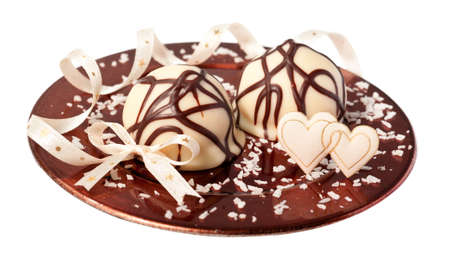 White chocolate truffle and satin hearts on a plate sprinkled with cocos shavings, isolated on whiteの写真素材