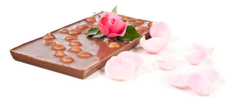 Chocolate bar with hasel nuts, a rose and rose petals on white backgroundの写真素材