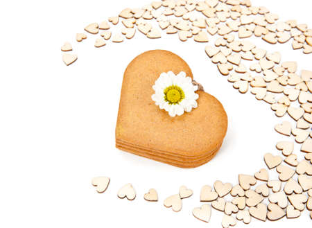 Stack of heart-shaped gingerbread cookies among smaller cardboard heartsの写真素材