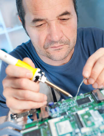 Senior male tech is soldering circuit boardの写真素材