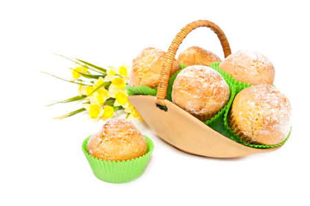 Basket full of muffins decorated with yellow daffodils on white backgroundの写真素材