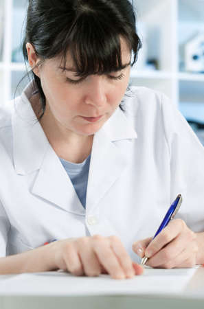 Scientist or a medic in a white coat making notes の写真素材