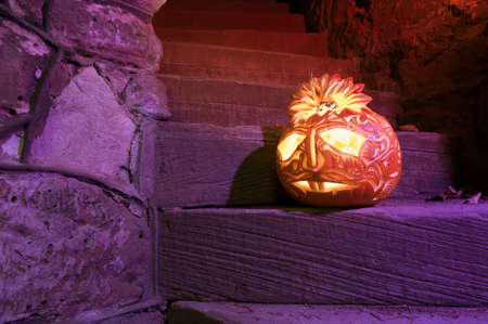 Halloween pumpkin with candle inside on purple-lit ancient staircaseの写真素材