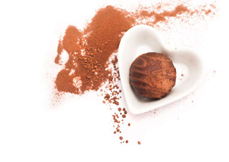 Chocolate praline in a heart-shaped plate on white backgroundの写真素材