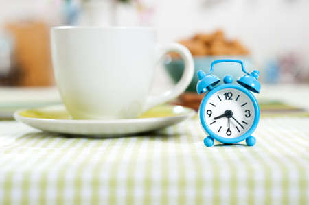 Blue alarm clock on a table laid down for breakfast の写真素材
