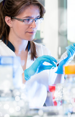 Scientist with an automatic pipette in modern laboratory, shallow DOF 