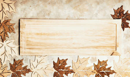 Artificial marple leaves on textured background around wooden board, spaceの写真素材