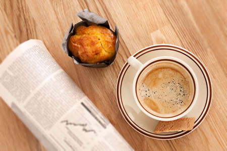 Coffee, muffin and rolled buisiness newspaperの写真素材