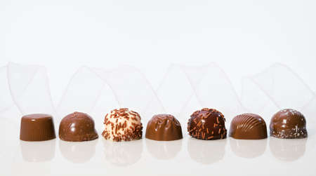 Chocolate pralines in a row with transparent white ribbon, text spaceの写真素材