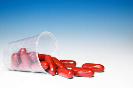 Closeup on dark red capsules with medication on blue gradient background の写真素材