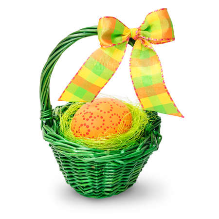 Orange Easter Egg with point circles in a green straw basket with a bow isolated on white の写真素材