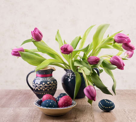 Bunch of tulips and painted Easter Eggs on a tableの写真素材