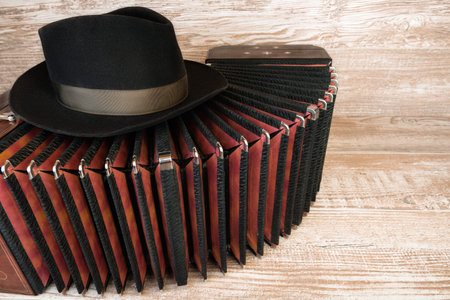 Bandoneon on wooden with a male black hat on top, text space