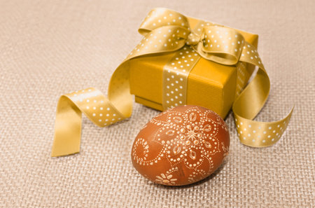 Decorated Easter Egg and a gift box on sachcloth