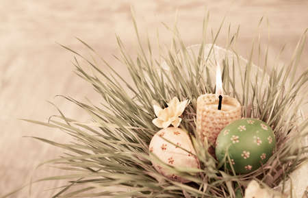 Bunch of grass with Easter Eggs and a burning candle, text spaceの写真素材