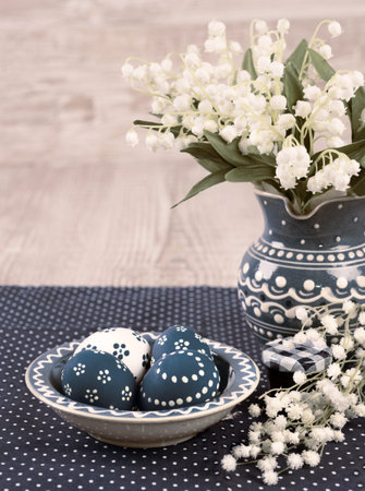 Blue and white Easter eggs and spring flowers on wooden background, text space