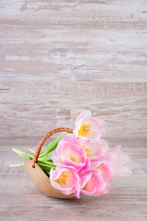 Pink tulips in the basket on wooden backgroundの写真素材