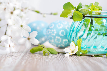 Cherry blossoms and Easter eggs on wooden table, text space, shallow DOF, focus on the jar and...