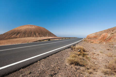 Modern road on Fuerteventura goes by ancient volcano の写真素材
