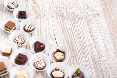 Wooden background with a row of chocolate pralines, text spaceの写真素材