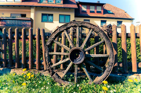 Old wooden wheels in front of traditional rural house in Germany, toned imageの写真素材