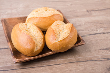 Wheat bread rolls on wooden plate