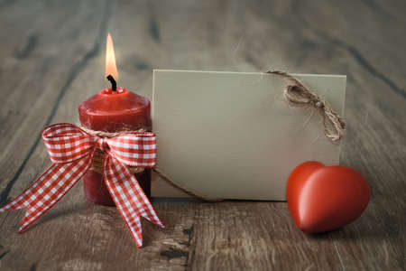 Blank greeting card with burning candle and stuffed checked heart. Space for your textの写真素材