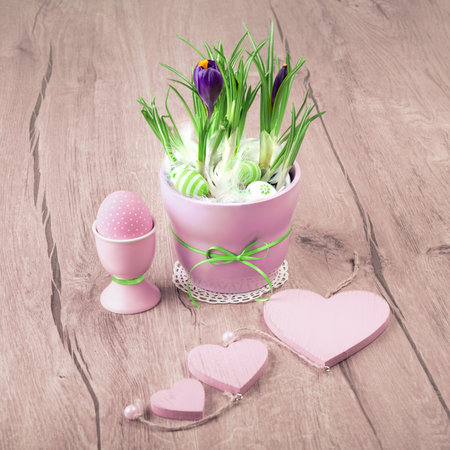 Crocus flowerpot and pink Easter decorations on wood