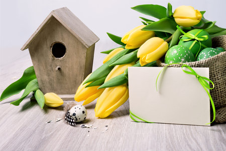 Easter border with yellow tulips and natural decorations on neutral background