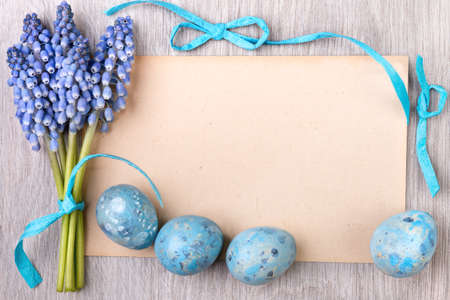 Blank paper card framed by blue ribbons, Easter eggs and grape hyacinth flowers, space for your textの写真素材