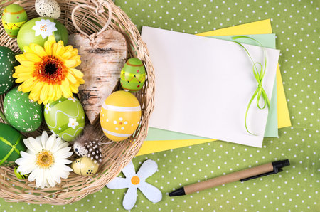 Easter frame with eggs, flowers and decoations, with a paper card for your text.の写真素材