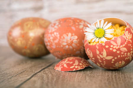 Easter eggs and margarita flower on wooden table, shallow DOF, focus on the flower petals and part of right eggの写真素材