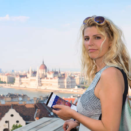 Attractive blonde female traveller with a travel book in central Budapest. Pattern on the cover has been generated for this image.の写真素材