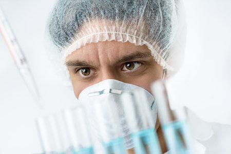 Keen scientist with brown eyes in protective wear performs protein assayの写真素材