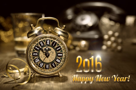 Composition with vintage alarm clock showing five to midnight and an old phone. Happy New Year 2016!