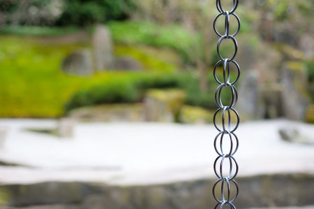 Oriental background. Rain chain in formal japanese garden, garden grounds out of focus, space for...